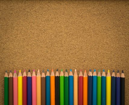 crayons put on a cork board view from top. free space for text. educations concept, back to school concept.