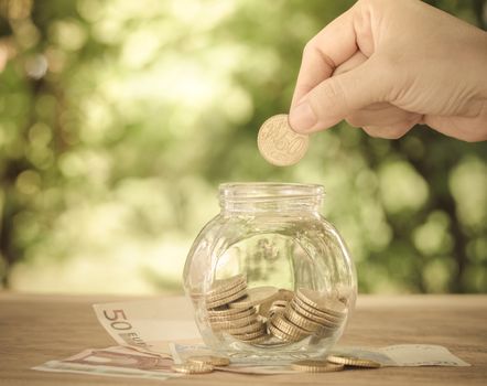 hand's women putting golden coin in money jar. account concept,business concept,finance concept. vintage style.