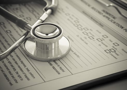stethoscope with medical record application form on physicians desk