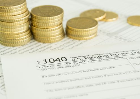 close-up income tax return form with golden coins on desk.