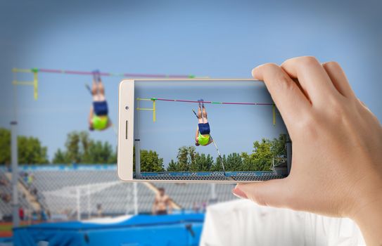  Hands with the phone close-up.Woman photographs sporting competitions athletes on smartphone