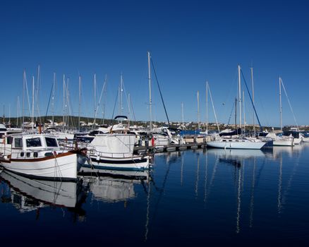 Various Anchor Yachts with Reflection in Surface of Sea in Marina of Mahon, Menorca, Spain