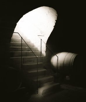 Vintage image with old stone stairs going into an antique cellar, with a strong beam of light coming down.