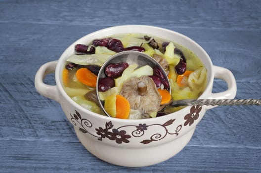 Vegetable soup with red beans and mushrooms, blue wooden background