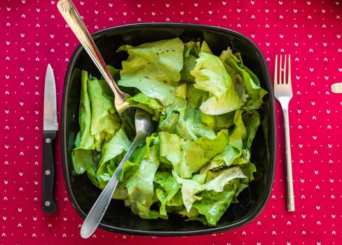 lettuce in a black bowl on a red tablecloth