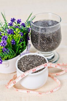 Healthy Chia seeds in white cup and soak in water with measuring tape on tablecloth.