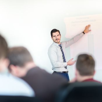 Business man making a presentation at office. Business executive delivering a presentation to his colleagues during meeting or in-house business training, explaining business plans to his employees.