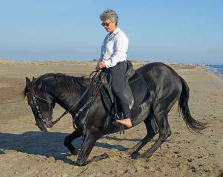 horsewoman making dressage with her stallion on the beach
