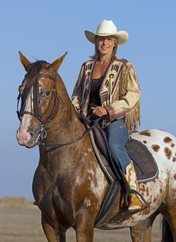 cowgirl on appaloosa horse on the beach