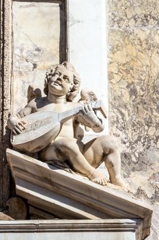 the statue of a cherub with a mandolin