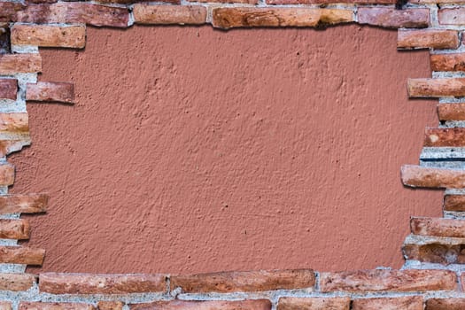 Ancient red brick wall with a hole over a bakground rose.