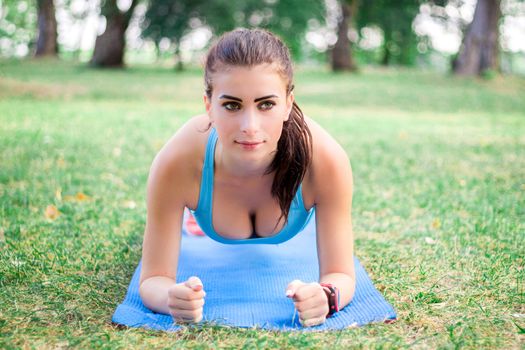 Young fitness girl doing plank during training workout outdoor