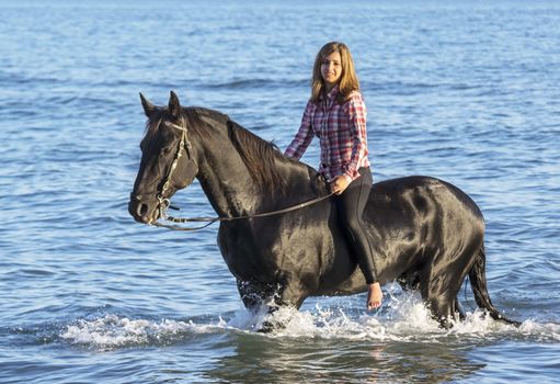 horse woman and her stallion riding in the sea