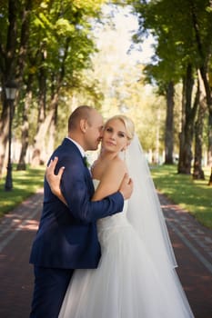 Newlyweds tenderly embraced in the park standing in the alley