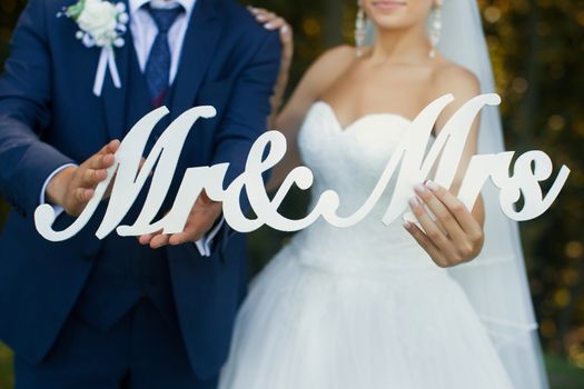 Newlyweds are holding the letters on a walk in the summer park