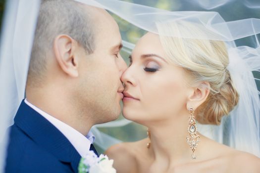 Amazing teen bride gently kisses the groom, close-up