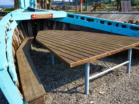 Creative outdoors picnic garden table seating corner made inside an old vintage traditional wooden boat