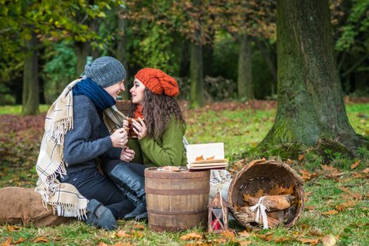 Happy romantic couple at fall drinking coffee in autumn garden