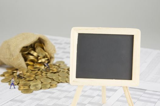 Close up empty blackboard on finance account have blur gold coins overflow from brown sack with construction worker as background.