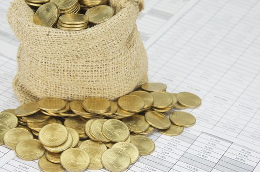 Close up stack of gold coins with brown sack of coins on finance account.