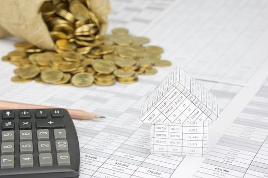 Close up house on finance account have blur calculator with pencil and gold coins overflow from brown sack as background.