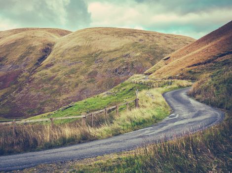 Winding Single Lane Road Up Through The Rugged Landscape Of The Scottish Borders