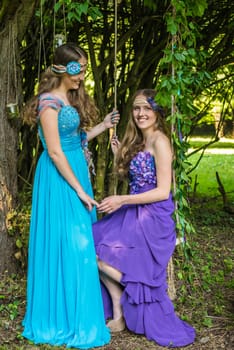 Beautiful happy smiling sisters twins in the garden with flowers and still life