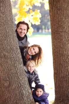 Happy family in autumn park near big tree trunk