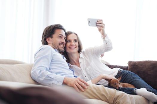 Happy couple taking a selfie together on the couch at home