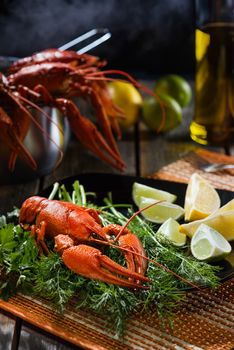 Boiled crayfish with fresh greens and a citrus on a black ceramic plate in style a rustic