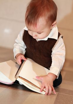 little boy studies a notebook, learns surrounding objects