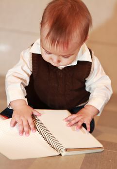 little boy studies a notebook, learns surrounding objects