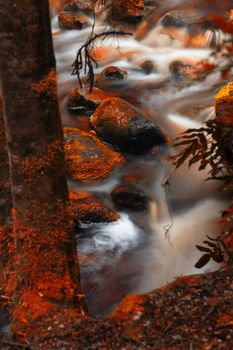 Newell creek in Tasmania, Australia is a magnificent fast running stream. Abstract landscape with red hues added.