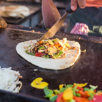 Chef making chicken with grilled vegetable tortilla wrap outdoor on street stall on Open kitchen international food festival event. Street food ready to serve on a food stall.