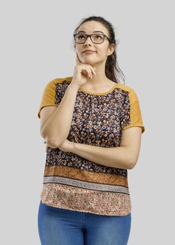 Beautiful and happy woman thinking, isolated over a gray background 