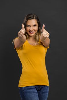 Beautiful woman in front of a dark wall and pointing to you