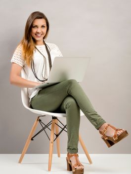 Beautiful woman sitting on a chair and working with a laptop