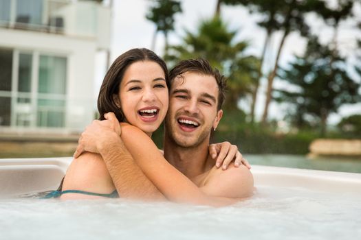 Young couple in a luxury hotel embraced inside a jacuzzi and enjoying the holidays