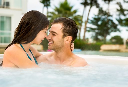 Young couple in a luxury hotel  inside a jacuzzi and kissing