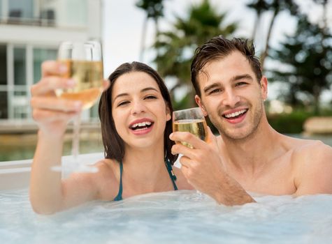 Young couple inside a jacuzzi and toasting 