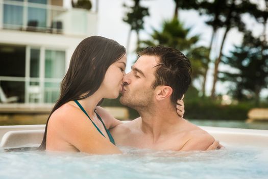 Young couple in a luxury hotel  inside a jacuzzi and kissing