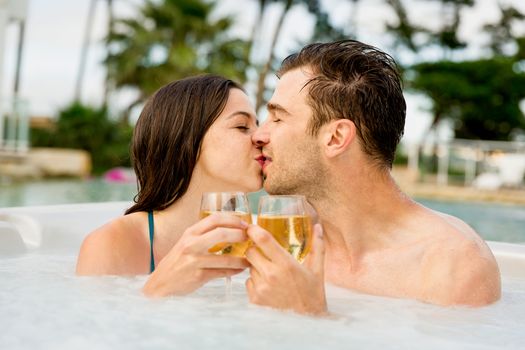 Young couple inside a jacuzzi dating and toasting 