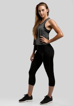 Young fitness woman against a gray background