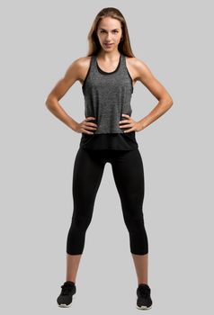 Young fitness woman against a gray background