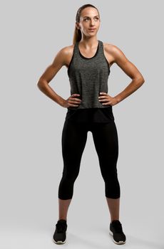 Young fitness woman against a gray background