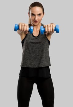 Young fitness woman making exercises with dumbbells