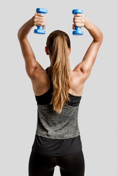 Young fitness woman making exercises with dumbbells