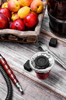 Smoking Arab hookah and wooden basket with plums