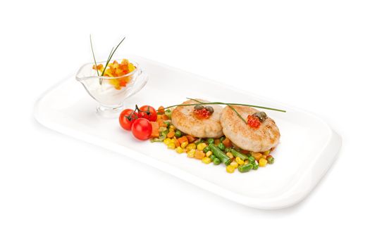 The dietary fish cutlets served on a white dish with a garnish from corn and asparagus haricot, with sauce, decorated by red caviar,  isolated on a white background.