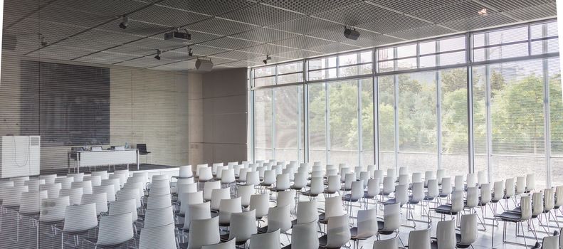 Interior of empty contemporary conference hall with white chairs.